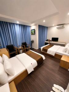 two beds in a hotel room with blue curtains at Hotel Royal in Vân Lũng