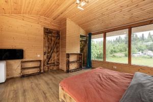 a bedroom with a bed and a tv in a wooden room at Heshkili huts and cabins Svaneti in Keshkili