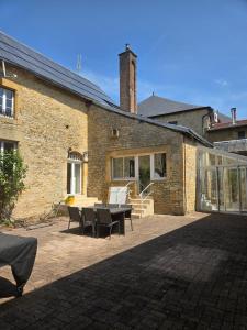 a brick building with a patio with a table and chairs at L'Argonnière in Buzancy