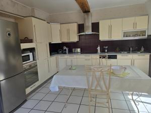 a kitchen with white cabinets and a table and chairs at L'Argonnière in Buzancy