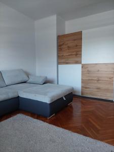 a living room with a bed and wooden floors at Dodi Apartman in Vonyarcvashegy
