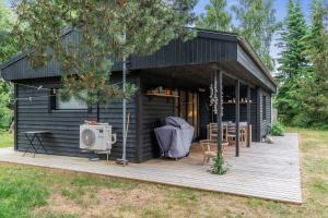 eine schwarze Hütte mit Holzterrasse auf einem Feld in der Unterkunft Ferienhaus In Der Nähe Eines Schönen Sandstrandes in Gedser