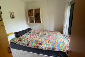 ein kleines Schlafzimmer mit einem Bett und einer bunten Steppdecke in der Unterkunft Ferienhaus In Der Nähe Eines Schönen Sandstrandes in Gedser