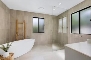 a bathroom with a large tub and a shower at Wyuna Drive 53 in Noosaville +13 photos