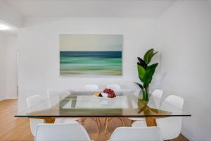 a dining room with a glass table and white chairs at Wyuna Drive 53 in Noosaville