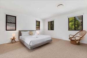 a white bedroom with a bed and a chair at Wyuna Drive 53 in Noosaville