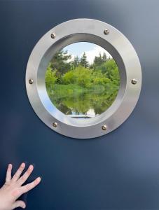 a hand reaches for a circular mirror on a wall at Pływający Dom in Zegrze