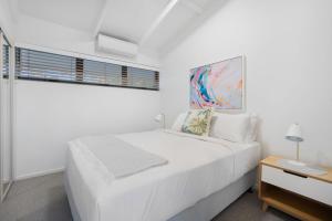 a white bedroom with a white bed and a window at Witta Circle 24 in Noosa Heads +8 photos