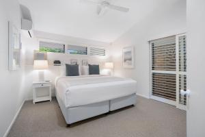 a white bedroom with a bed and a window at Witta Circle 24 in Noosa Heads