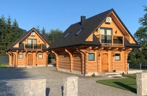 a large wooden cabin with a black roof at Bałtowska Osada in Bałtów