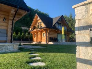 a log home with a pathway in the yard at Bałtowska Osada in Bałtów