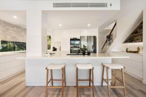 a kitchen with white cabinets and bar stools at Townhouse 6 Sunseeker Close 26 in Noosaville