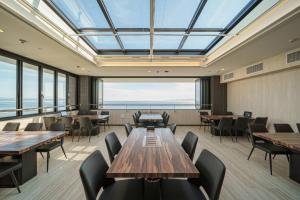 a restaurant with wooden tables and chairs and large windows at Apartment Hotel YAEZAKI in Beppu