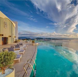 a hotel pool with chairs and a view of the water at Crystal Bay Premier Suites in Nha Trang