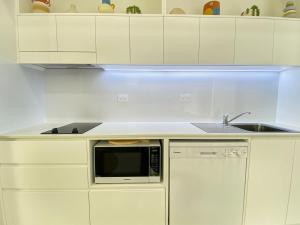 a white kitchen with a sink and a microwave at Rock Salt Villa 2 in Picnic Bay
