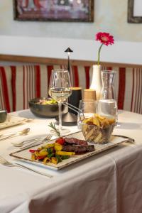 a table with a plate of food and a glass of wine at Hotel Zum Stern inkl Gasteiner Bergbahnen im Sommer in Bad Hofgastein