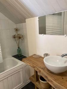 a bathroom with a sink and a tub and a mirror at La maison d'André in Laurière