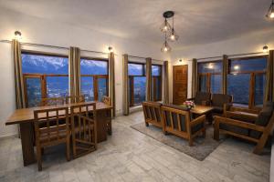 a living room with a table and chairs and windows at The Himalayan Nomad Manali - 2 bedrooms mountain view independent villas with personal lawn in Manāli
