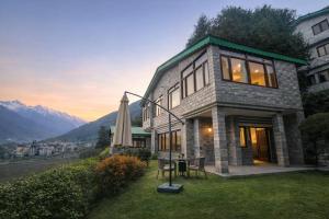 a stone house with a table and a umbrella at The Himalayan Nomad Manali - 2 bedrooms mountain view independent villas with personal lawn in Manāli