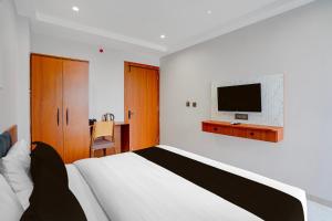 a bedroom with a bed and a tv on a wall at Townhouse Oak Ujjain Railway Station Formerly Kasliwal Inn in Ujjain