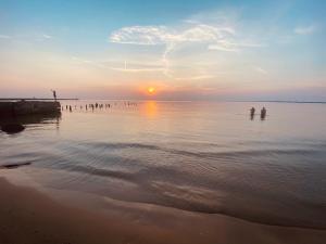 two people standing in the water at sunset at Acapulco Liepaja in Liepāja
