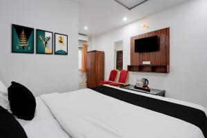 ein Schlafzimmer mit einem weißen Bett und einem Fernseher in der Unterkunft Super Collection O Taramandal Road Gorakhpur Formerly NS Hotel in Gorakhpur
