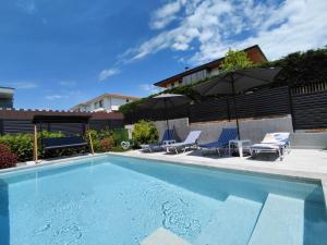 a swimming pool with chairs and umbrellas next to a house at Villa Calypso, private pool with heating and salt water in Lozenets