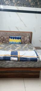a wooden bed with blue and yellow pillows on it at Hotel Gaurav in Ahār