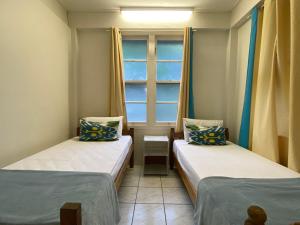 two beds in a small room with a window at The Captains Manor on Cook 8 in Arcadia