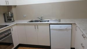 a white kitchen with a sink and a dishwasher at Magnetic Reef 7 in Arcadia