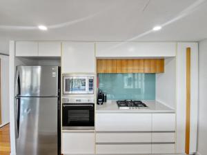 a kitchen with a stainless steel refrigerator and microwave at Maggies Beachfront Apartment 12 in Horseshoe Bay
