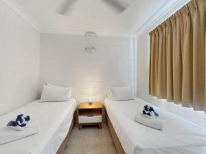 two twin beds in a room with a table at Arcadia Palms 1 in Arcadia