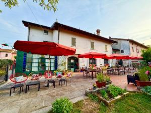 a patio with tables and chairs and red umbrellas at B&B La Borasca in Casalpusterlengo