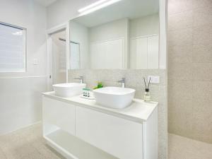 a white bathroom with two sinks and a mirror at Rock Salt Villa 1 in Picnic Bay
