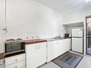 a white kitchen with white cabinets and a microwave at The Barracks Arcadia 2 in Arcadia