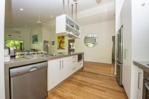a kitchen with white cabinets and a stainless steel refrigerator at Whispering Palms in Nelly Bay