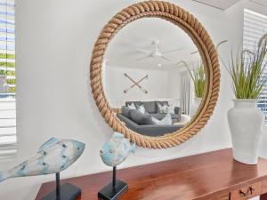 a round rattan mirror in a living room with a couch at Sails on Horseshoe Apartment 4 in Horseshoe Bay