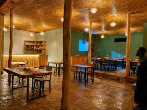 a man standing in a room with tables and chairs at Akagera Park Inn in Akagera