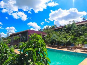 a pool at a resort with blue sky and clouds at Akagera Park Inn in Akagera