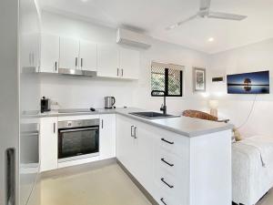 a kitchen with white cabinets and a sink at Kadani in Picnic Bay