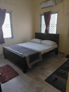 a large bed in a room with two windows at Villa Yogalakshmi in Chidambaram +3 photos