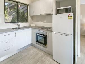 a kitchen with white cabinets and a refrigerator at Beachside Palms Unit 3 in Nelly Bay