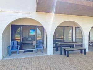 a patio with two chairs and a table and benches at Beachside Palms Unit 3 in Nelly Bay