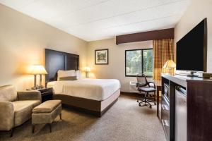 a hotel room with a bed and a television at Baymont by Wyndham Janesville in Janesville