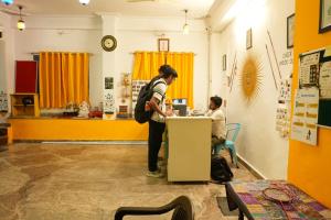 two people standing at a counter in a room at Hostel Mama in Udaipur