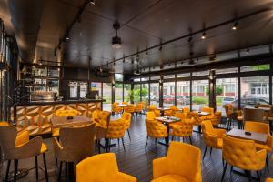 a restaurant with yellow chairs and tables and windows at Vila Hera Spa in Vrbas
