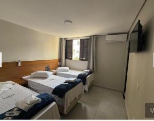 a room with three beds and a window at Hotel New City in Guarulhos