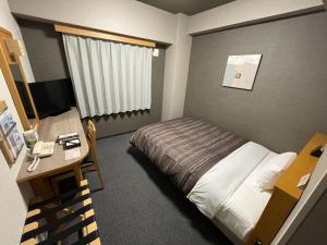 a bedroom with a bed and a desk with a computer at Hotel Route-Inn Yukuhashi in Yukuhashi