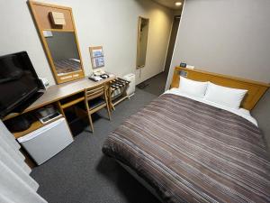 a hotel room with a bed and a desk and a television at Hotel Route-Inn Yukuhashi in Yukuhashi +22 photos
