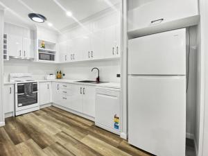 a white kitchen with white cabinets and a refrigerator at Magnetic Reef Unit 2 in Arcadia